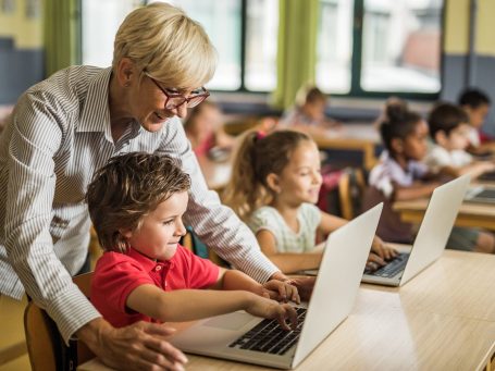 Eine Lehrerin hilft beim Arbeiten am Computer.