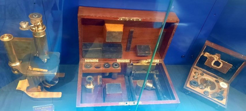 Mikroskop und Linsen in einer Vitrine